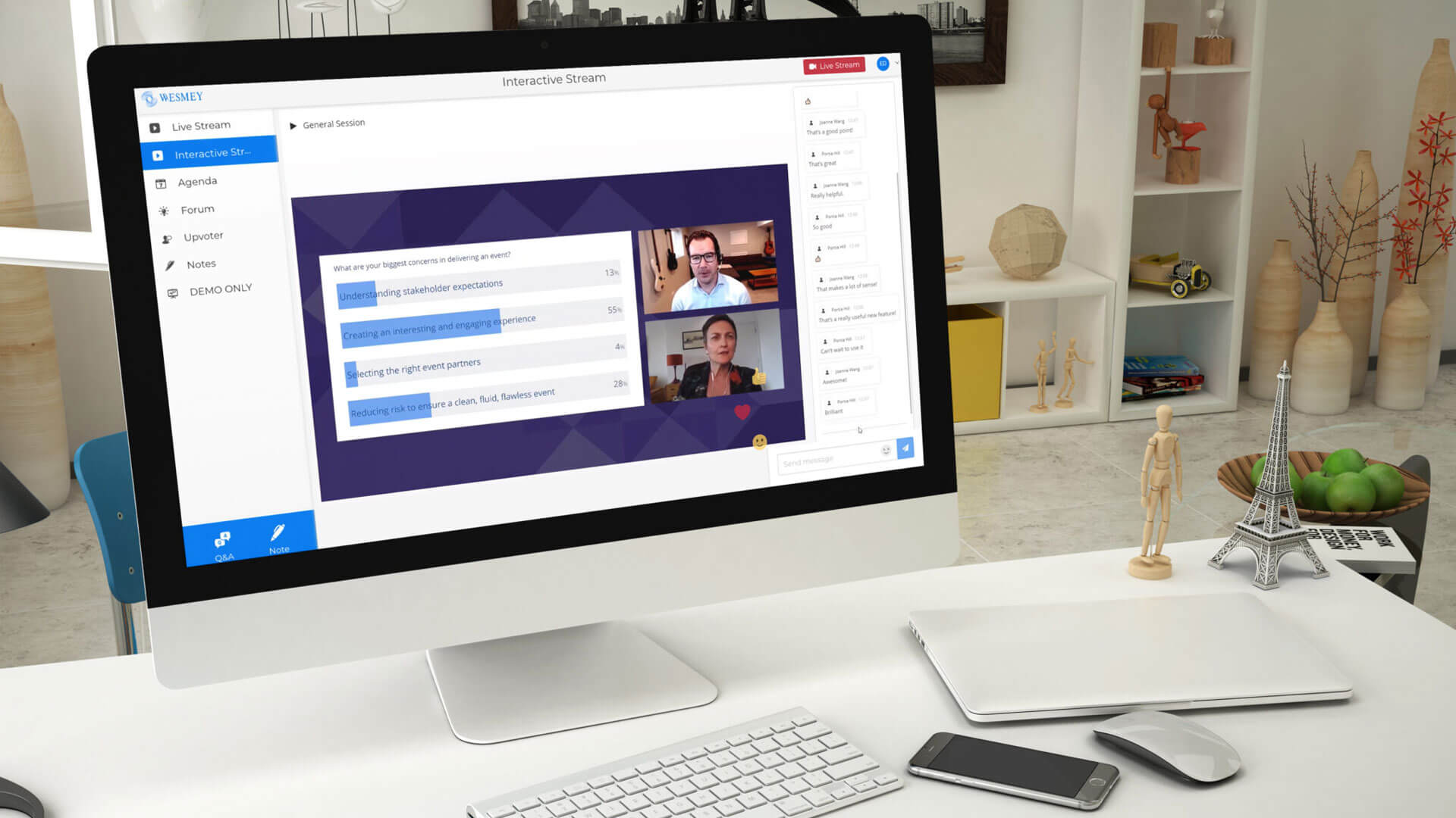 Un écran d’ordinateur sur un bureau affiche une réunion virtuelle avec deux participants et un partage d’écran. Le bureau comprend un clavier, une souris, un téléphone, un bloc-notes et des articles décoratifs dont une petite tour Eiffel.