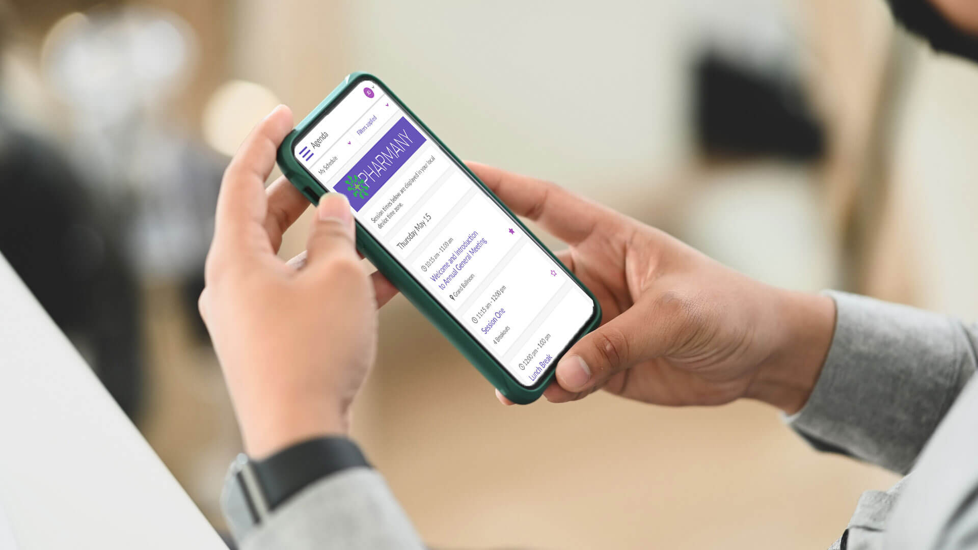 A person holding a smartphone displays the Pharmanavi website, showing navigation options for pharmacy-related study resources on the screen. The background is blurred, focusing on the phone.