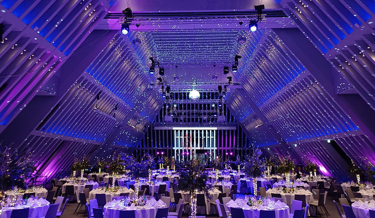 Grande salle de banquet décorée avec des lumières violettes et bleues.